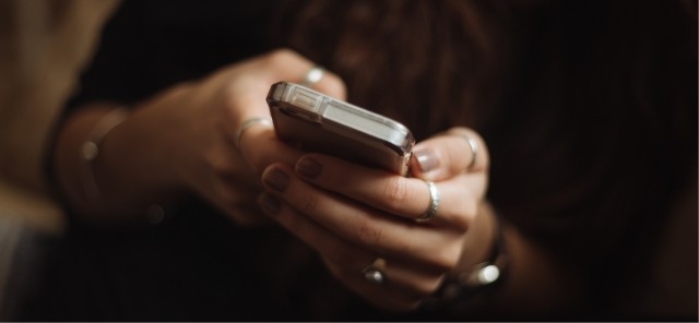 Hands in the dark holding a mobile phone