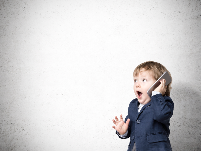 A young boy holding a phone to his ear with a surprised look on his face