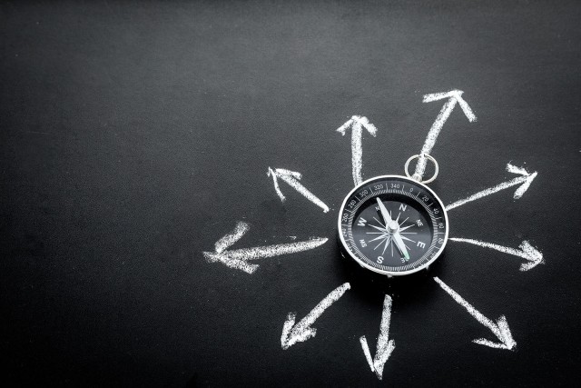 Direction of movement, travel direction. Compass among the arrows on black background top view copy space