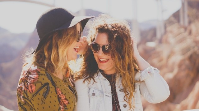 Two women standing next to each other laughing and sharing a joke